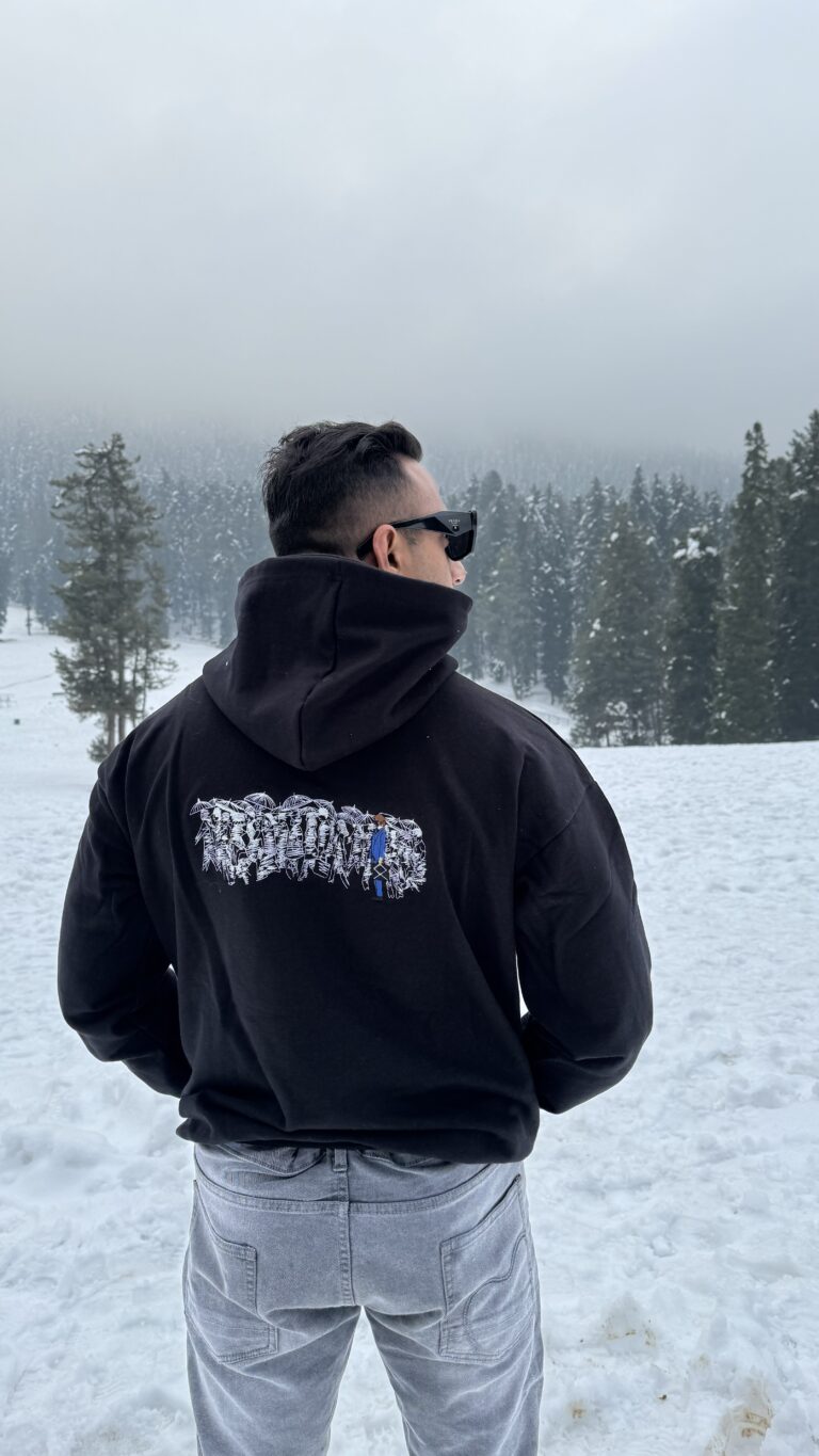 Person in a Karoshi embroidered hoodie amidst snowfall.